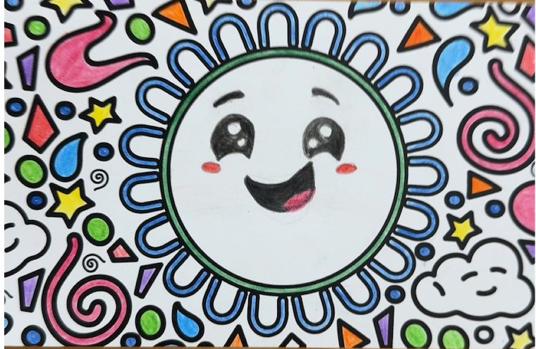 Close-up of a finished card: a smiling face inside a green sun ringed with blue petals